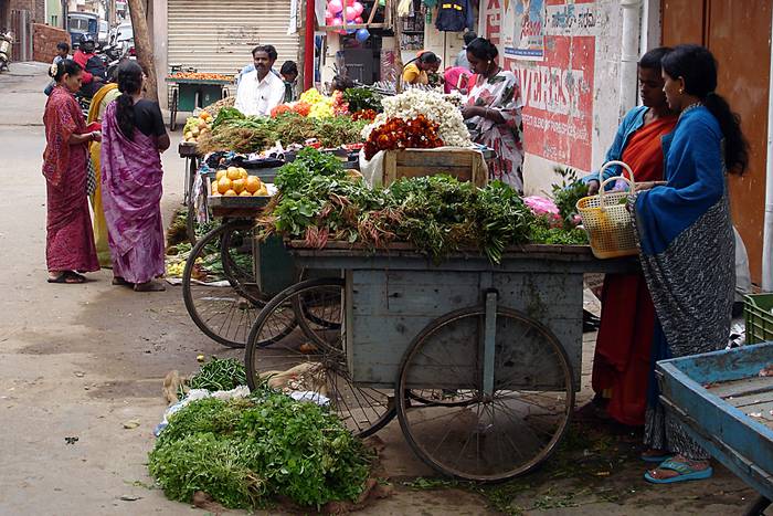 Frauen verkaufen Gemüse von einem Handwagen.