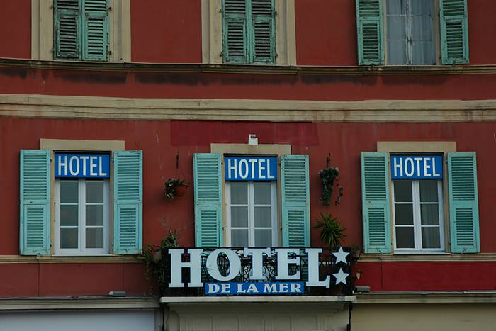 Fassade eines rötlichen Hauses mit der Aufschrift "Hotel de la Mer" und 2 Sternen.