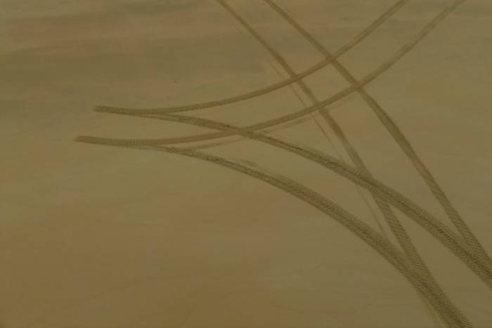 Reifenspuren auf einem Sandstrand.